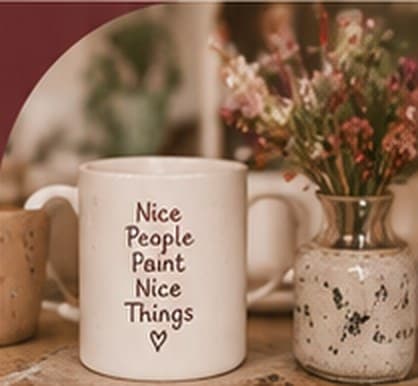 Mok met de tekst Nice People Paint Nice Things naast een vaasje bloemen